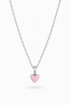 A delicate silver chain necklace featuring a small, polished silver heart pendant with a smooth, light pink enamel center, displayed against a clean white background.
