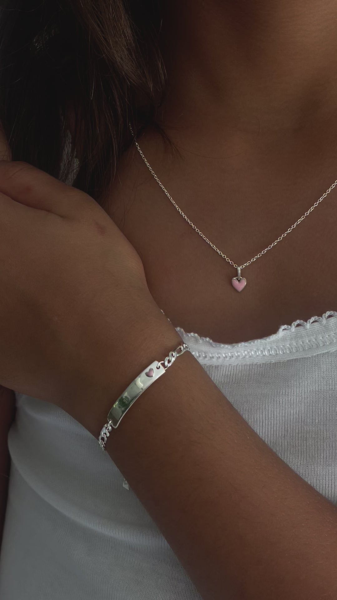 A close up video showing the Pink Petite Darling Necklace and Pink Darling Bracelet on a young girl.