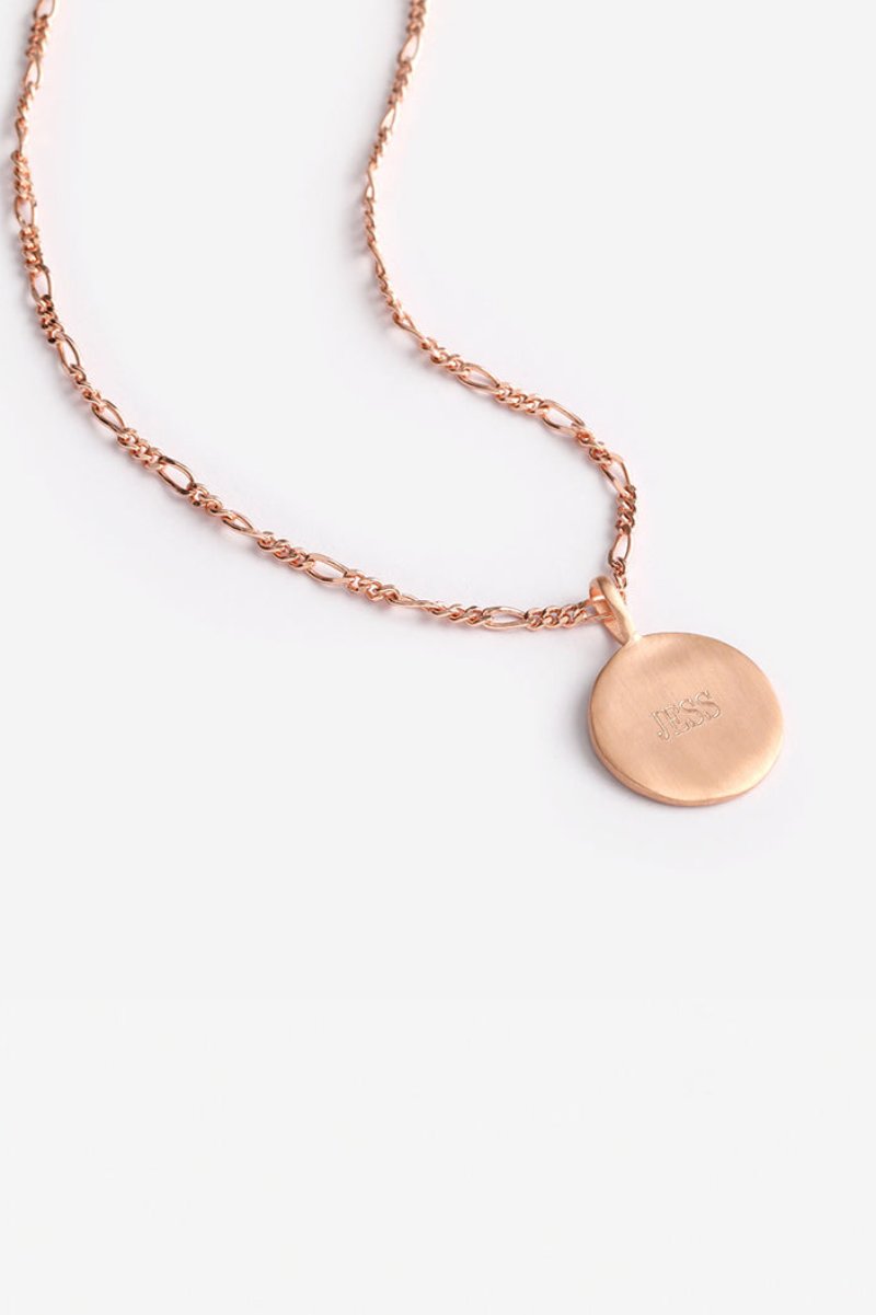 Engraved rose gold disc necklace on Figaro chain shown against plain background