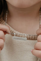 Child’s hands holding the Signature Bar Necklace Silver engraved with “MILLA”. A sweet, meaningful gift for kids or loved ones.