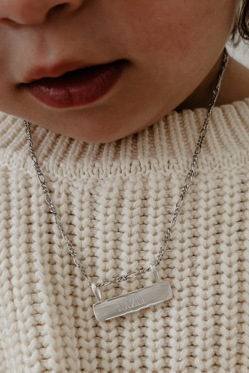 Signature Bar Necklace Silver engraved with “NAZLI” shown on a child’s chest. A cherished personalised necklace for everyday wear.
