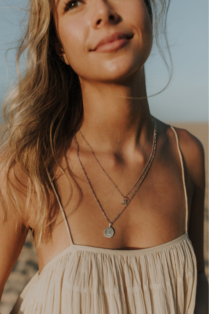 Layered silver engraved pendant necklaces with fine chains.