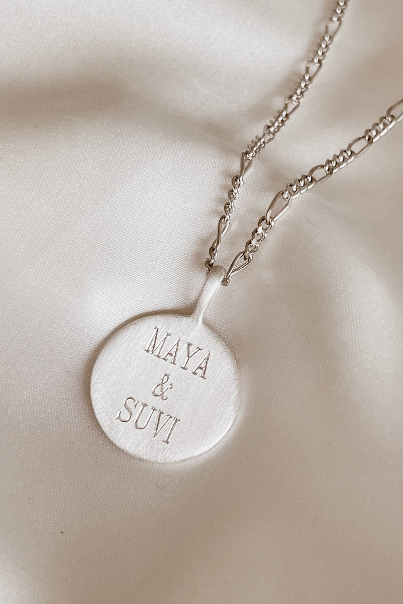 Silver round pendant necklace engraved with two names.