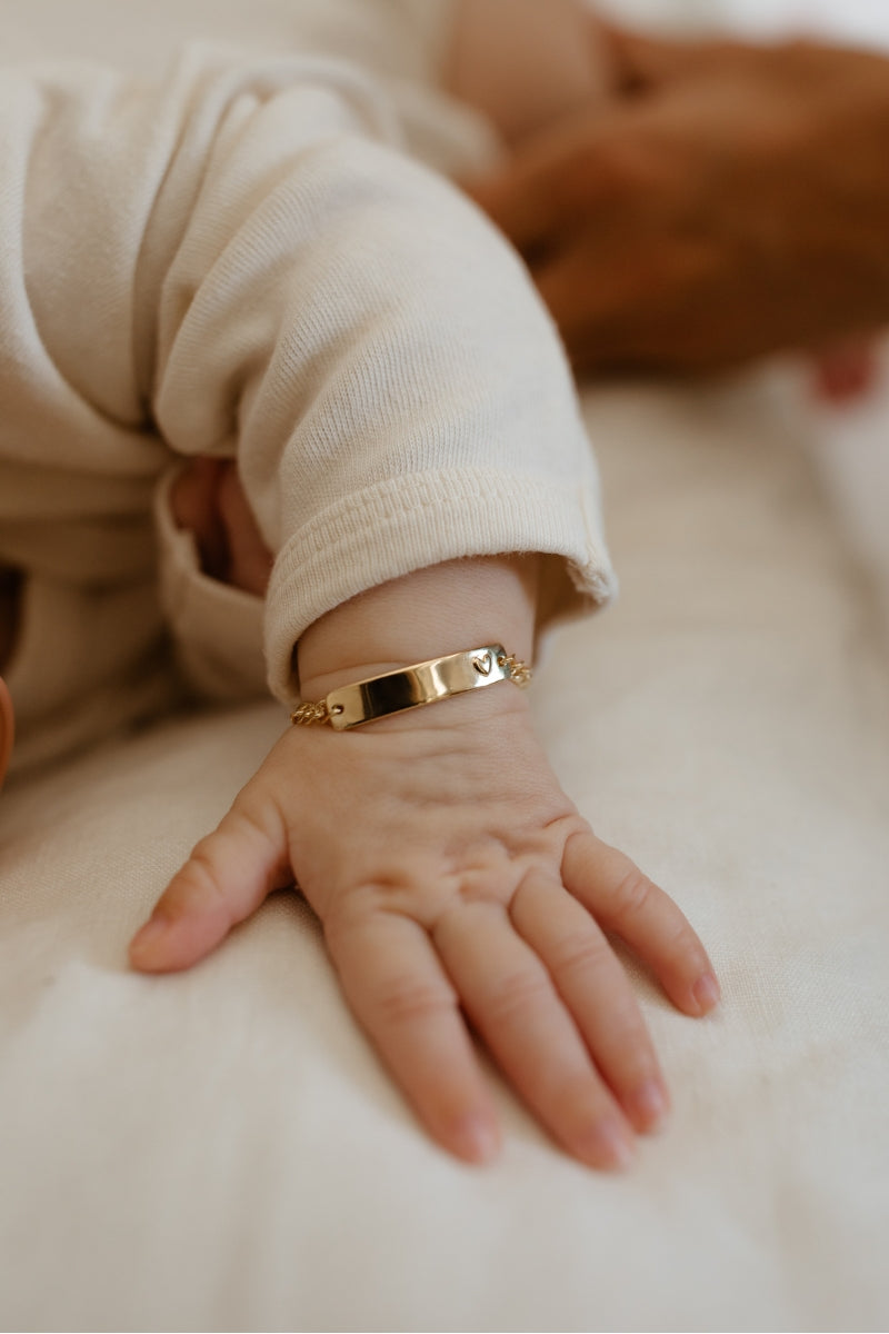 Baby wearing solid gold Darling Bracelet with engraved nameplate and heart detail, a forever keepsake piece by Bluebird Jewellery