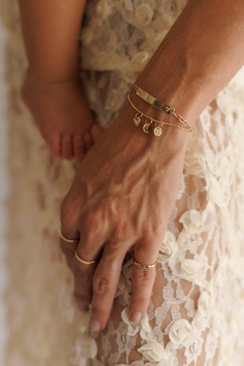 Mum wearing stacked solid gold Darling Bracelet with engraved pendants by Bluebird Jewellery