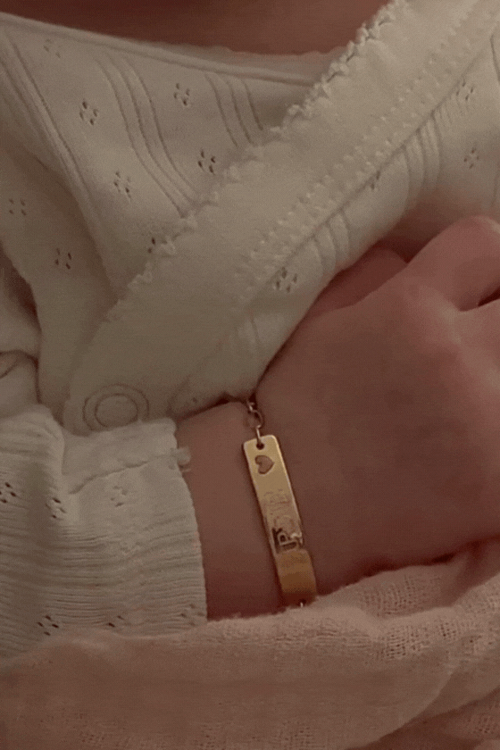 Baby wearing an engraved 9ct solid gold Pink Darling Bracelet with a pink heart charm by Bluebird Jewellery, crafted as a timeless keepsake. 