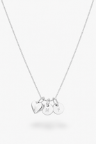 A silver chain necklace with three small hanging charms: a heart-shaped charm and two round disc charms engraved with the letters M, F, and S, shown on a light gray background.