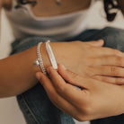 A Signature Bracelet is being held to show the under side where a date of birth has been engraved.