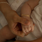 A four month old girl is wearing the baby sized Daisy Bracelet in Gold Vermeil by Bluebird Jewellery
