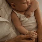 A baby girl is wearing the Daisy Bracelet in Gold Vermeil by Bluebird Jewellery.