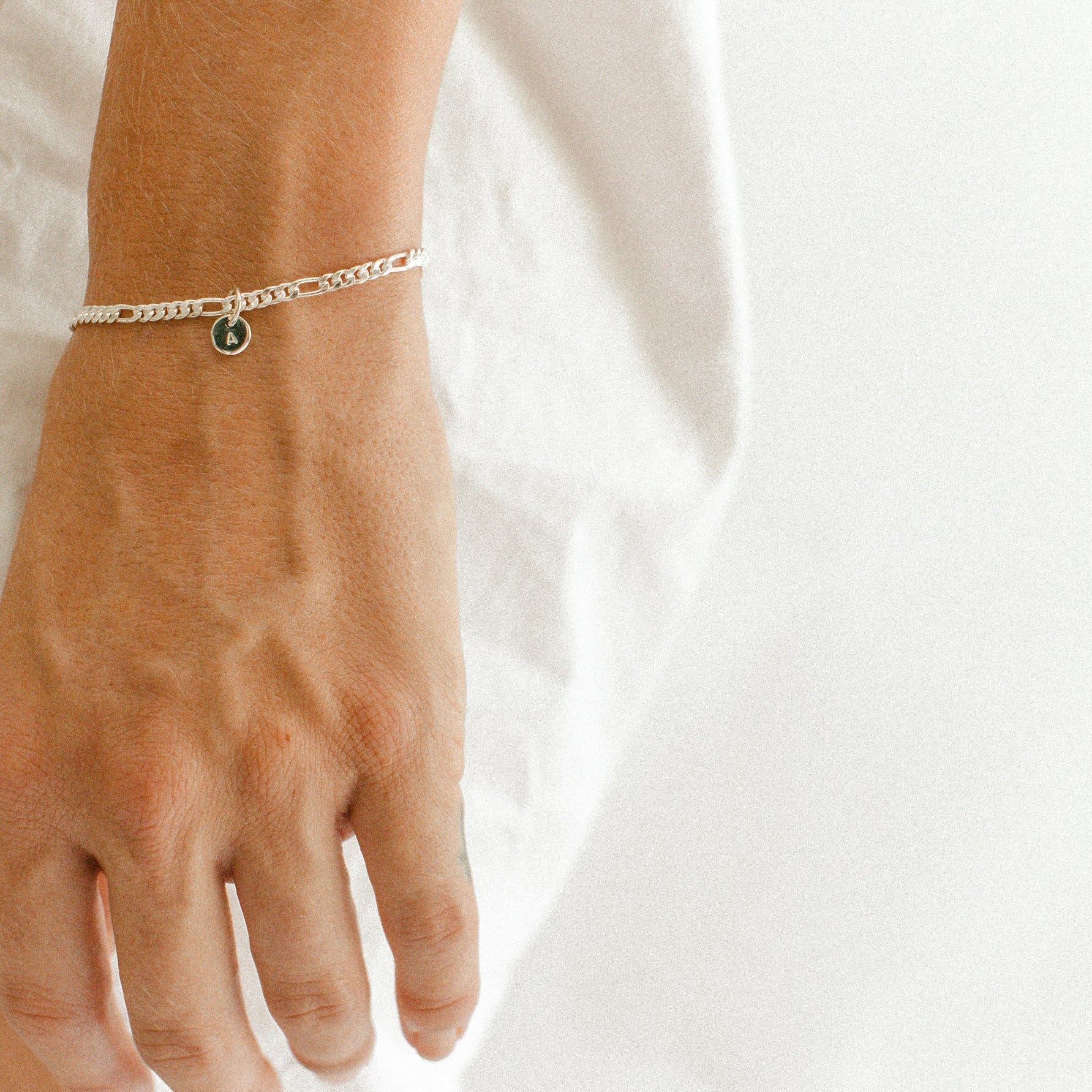 A Figaro Bracelet in adult length worn with one 6mm initial pendant by Bluebird Jewellery