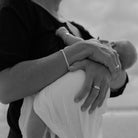 A mother wears a Vintage Pearl Signet Ring on her ring finger as she holds her newborn baby.