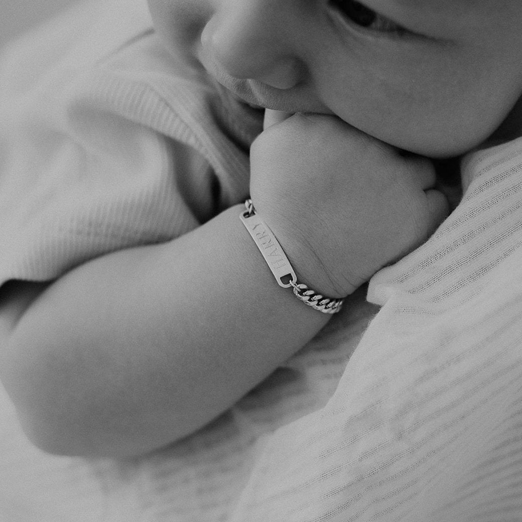 A baby boy wears his baby length Classic ID bracelet with his name engraved on the front of the bracelet.  The bracelet is made from solid sterling silver and is a timeless keepsake bracelet that is available in child and baby adjustable lengths.