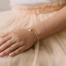 A child wearing a delicate gold Lace Chain bracelet featuring a mermaid shell charm, crafted as a timeless keepsake.