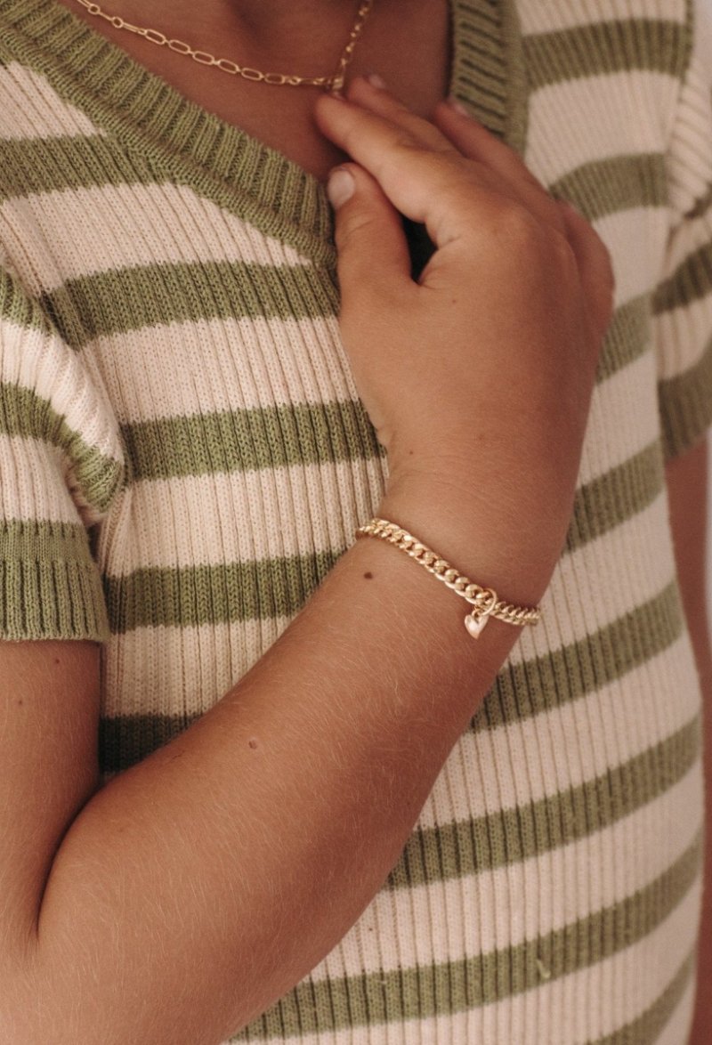 A young girl wearing a gold Sweetheart Cuban Link Chain and polished heart pendant, designed as a timeless keepsake piece.