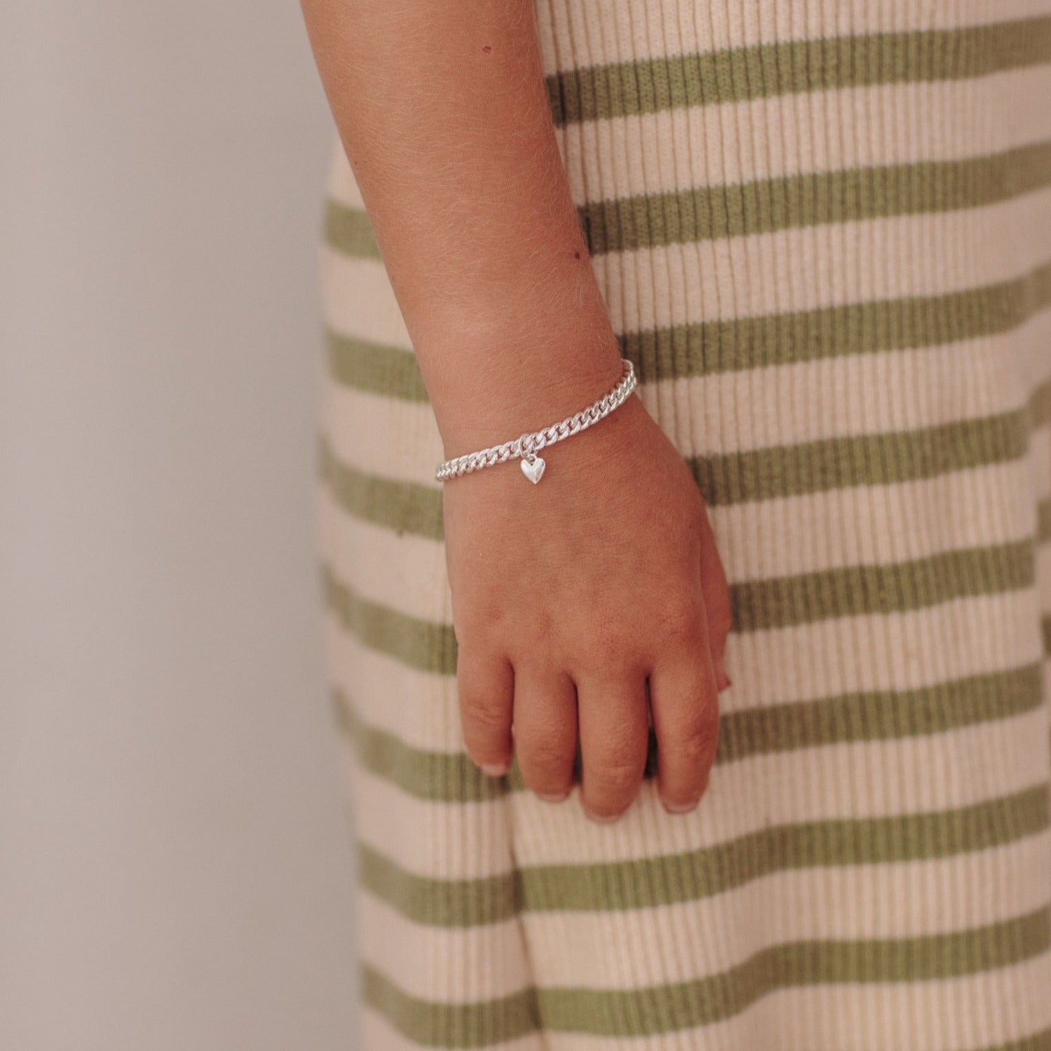 sterling silver cuban link bracelet with a mini sweetheart pendant in sterling silver sits effortlessly on child's wrist.